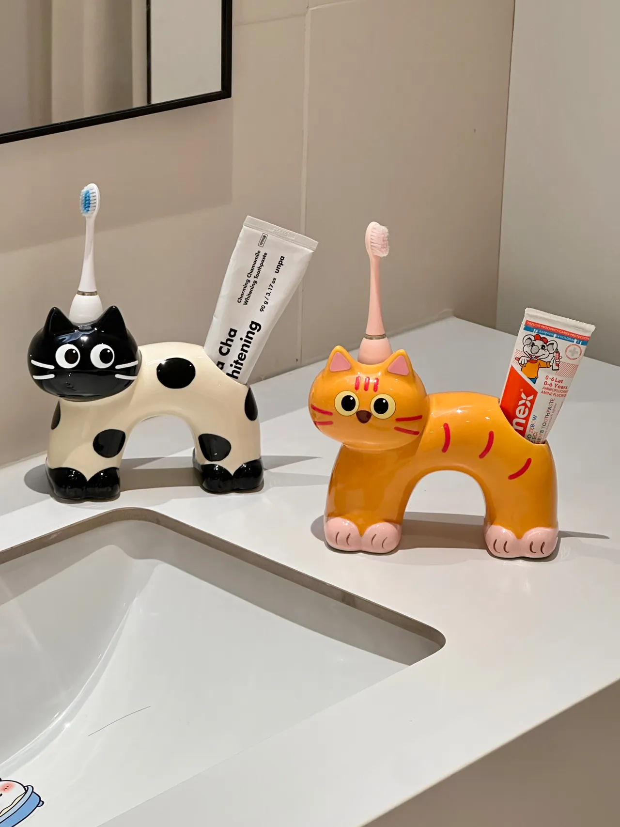 Ceramic cat toothbrush holders arranged on a bathroom counter